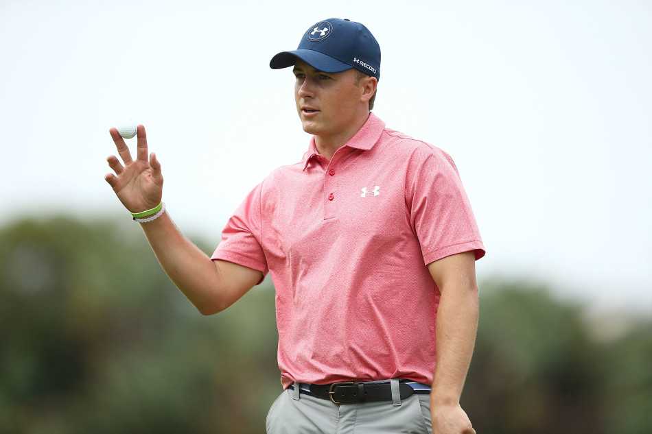 乔丹·斯皮思在球道边与球童专注商讨下一杆策略，手指方向正在分析最佳进攻路线。