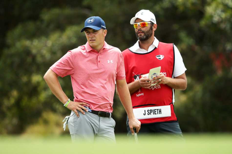 乔丹·斯皮思在果岭边全神贯注地俯身观察推杆线路，寻找小球滚动的细微转折点。