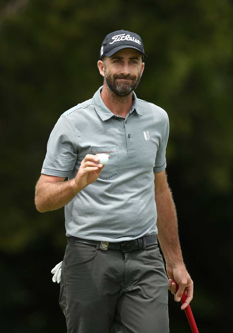 杰夫·奥格维在果岭上屈膝仔细研读推杆线路，手指轻触草皮感受坡度变化。