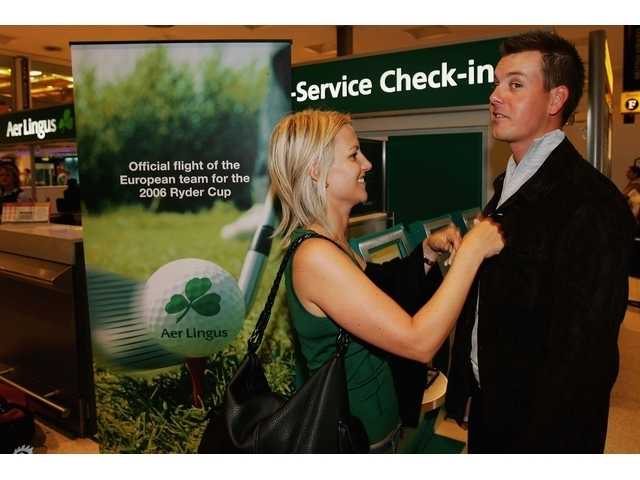 果岭之恋:高球伴侣的温情时刻 艾玛面带微笑,正细致地为斯滕森调整衣领,斯滕森眼神温和,展现出赛前片刻的宁静与默契