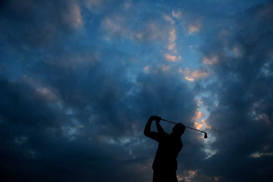 金色夕阳为球场披上霞光，球员挥杆的剪影与广阔天地融为一体，意境深远。