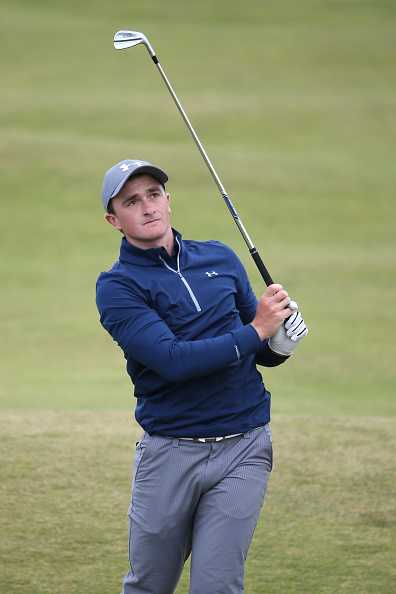 沙坑边缘，保罗·邓恩凝神屏息，正准备挥杆，沙粒在脚边闪烁着金色的光芒。