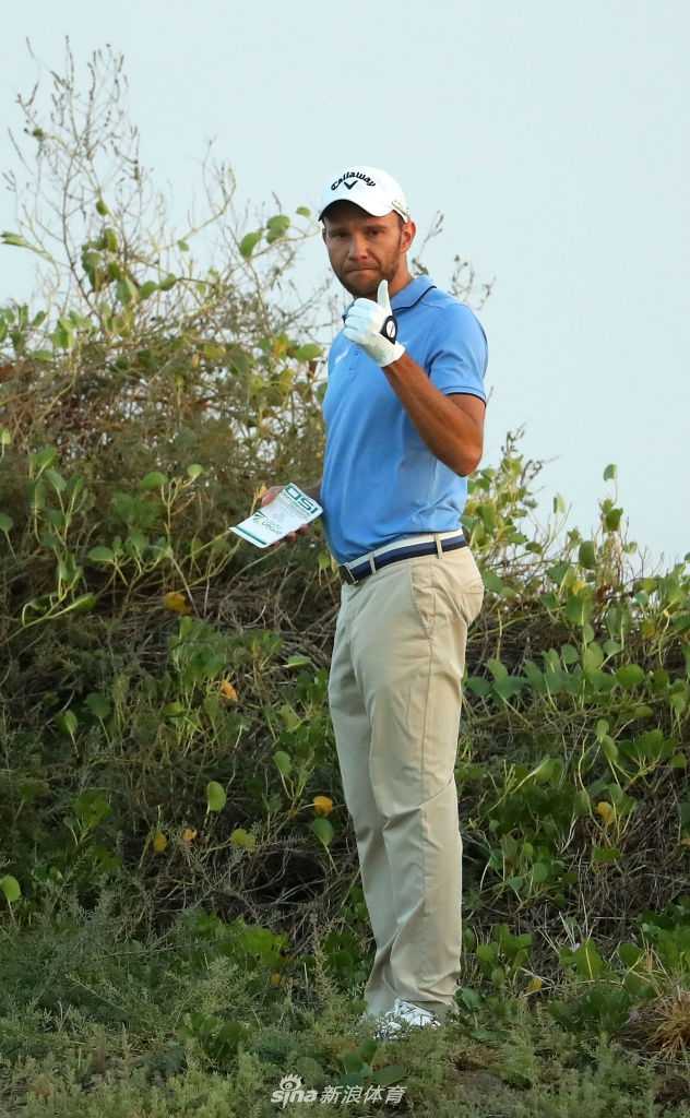 库尔特北山果岭边细心观察推杆线路，表情沉静而专注，手中推杆在沙漠阳光下微微反光。