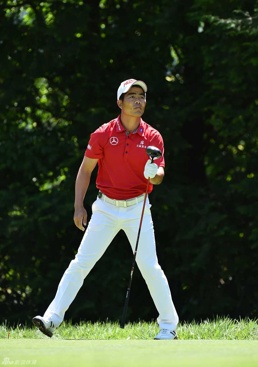 梁文冲在发球台眺望远方落点，背景是宁静的湖水与天空，动与静在此刻构成一幅充满张力的赛场画卷。