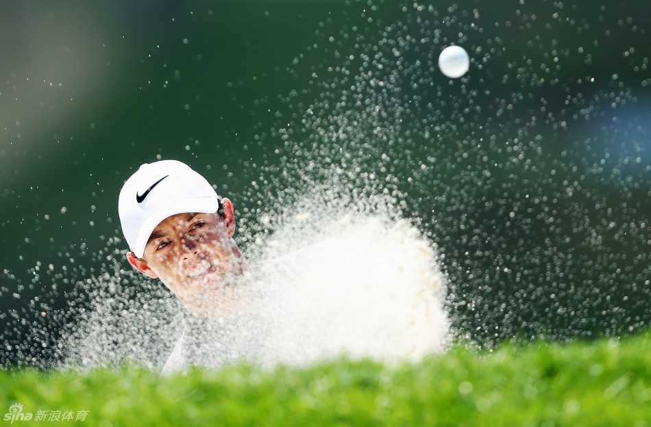 罗里·麦克罗伊在球道沙坑中救球，他双膝微屈，目光锐利地锁定小球，展现出世界级球员将球从困境中拯救出来的决心与技巧。