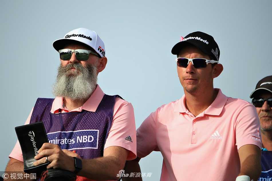 球员在碧蓝的水障碍旁谨慎击球，水面的倒影与远处迪拜的现代天际线构成一幅动静结合的运动美景。