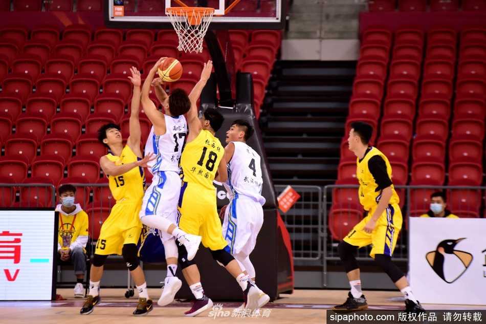 武汉当代内线悍将华刚辉在对方多人围堵下高高跃起，用指尖轻轻一点，将篮板球拨向队友方向，尽显篮下统治力。