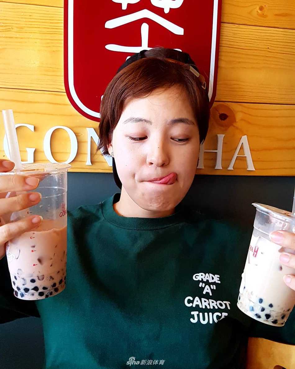 田仁智身着白色运动衫，阳光下短发熠熠生辉，露出自信从容的微笑