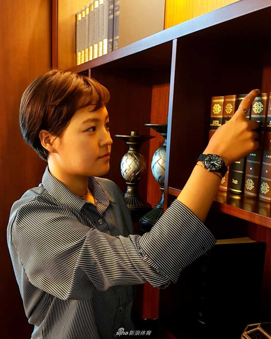 她手扶球杆驻足思考，短发造型让她的身影在广阔球场上显得格外利落与专注