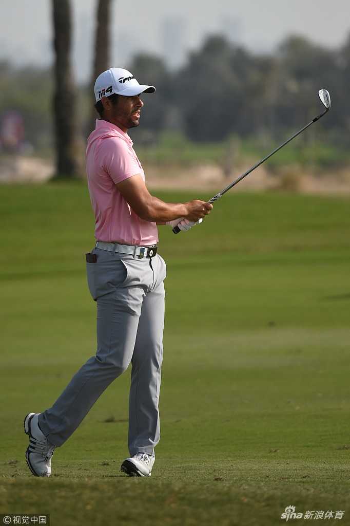 西班牙领先者奥塔圭在果岭上蹲身观察推杆线路，眼神锐利而专注