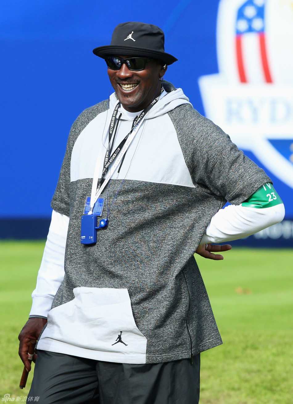 乔丹与球迷亲切互动，脸上带着标志性的微笑，在激烈的赛场边勾勒出一幅温馨画面。