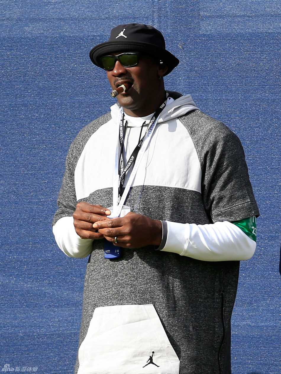 乔丹手搭凉棚远眺果岭，苏格兰的风吹动他的衣角，背景是起伏的球场与凝望的观众。